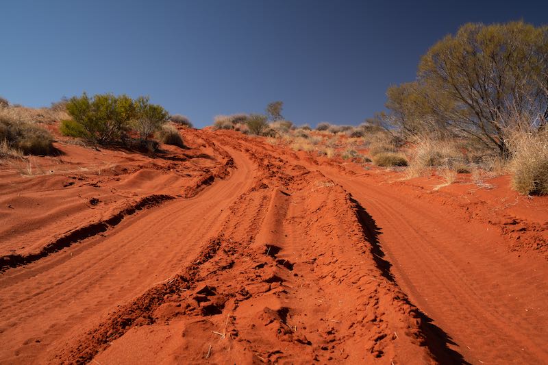 Red sand dune track with clear corrugation and washboard ridges under a blue sky